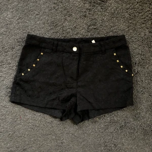 Shorts med nitar  - Shorts i mönstrat tyg. Ungefär storlek S. Nitar vid fickorna å kristall som knapp. Aldrig använda 