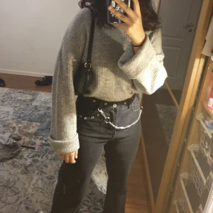 Grå stickad tröja - En mysig grå stickad tröja med hög krage och utsvängda armar. 