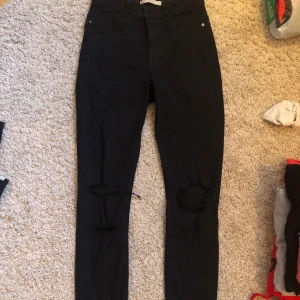 Svarta jeans med hål  - Ett par svarta jeans med hål i från Ginatricot. Det finns en liten fläck på ena benet som inte vill gå bort som man ser på andra bilden. 