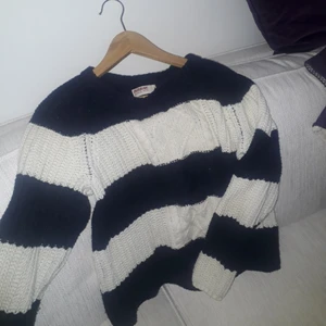  - En mysig stickad tröja ifrån  dobber. Den är randig  i vit och mörkblå. 