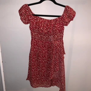 Söt klänning - Röd klänning med små blommor på. Finns ett litet hål vid armhålan. Kan skicka bild om man är intresserad.  Klänningen är en 34.