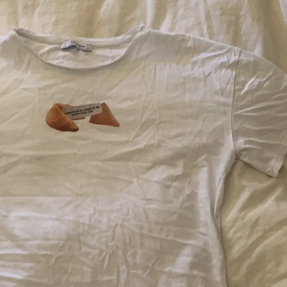En snygg vit t-shirt från Zara med fint motiv på framsidan, lite skrynklig på bilderna med allt tvättas och stryks innan det ska iväg till deras nya hem! Passar till allt och är extra fin nu i sommar🤩💕. T-shirts.