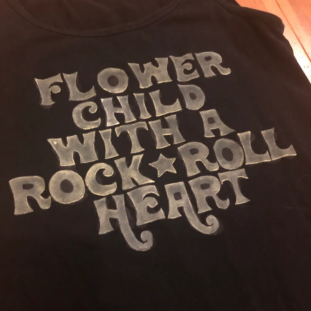 ”Flower Child With A Rock ⭐️ Roll Heart”. Målat linne svart med ljust gul text. Litet hål på baksidan längs kanten. Tar swish. Frakt ingår. 🤗. Toppar.