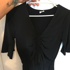 Festlig topp  - En svart topp med snöre där framme som justerar hur man vill ha toppen och urringningen, fåtal använd 