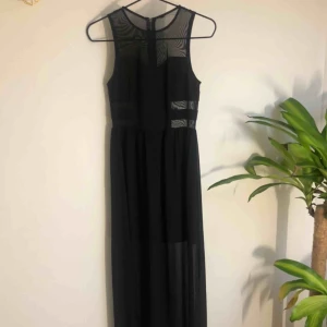  - Svart långklänning med meshtyg. Dragkedja i ryggen.