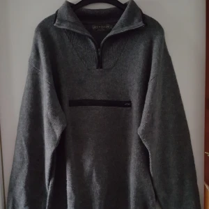  - Vintage grå stickad tröja med ficka framtill i storlek L. Snöre nedtill där det går att dra åt. Fraktkostnad blir 110kr.
