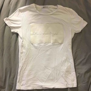  - Vit Calvin Klein T-shirt. Vitt tryck som är annat material än själva T-shirten. Litet hål vid texten se bild 2. Annars bra skick! Pris går att diskutera!🌼