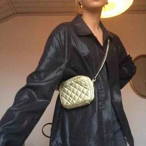 Guldig väska - Söt guldig väska med guldkedja! Går att använda som crossbody bag eller one shoulder bag! Själva väskbandet består av guldkedja och det guldiga  väsktyget, den är egentligen längre men jag har knutit det på bilderna!  Möts upp i Stockholm eller skickar!