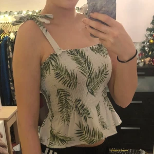 H&M linne Stl Xs - Somrigt vitt linne med palmer och rosetter vid axlarna från H&M stl Xs.