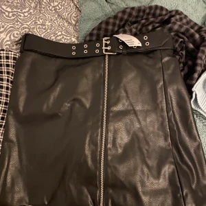 Cool kjol - HELT NY kjol i läderimitation. Jätte cool med dragkedja hela vägen ner samt skärp. Säljer då den är för stor på mig. Skulle säga att den passar M-L. Storlek 44