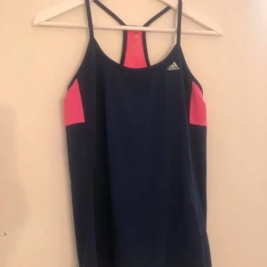 Adidas träningstopp strl S - Vad: Träningstopp från Adidas Storlek: S Material: huvudmaterial 84 % polyester, 16 % elestan, innerfoder 100 % polyester. Skick: Använd ett fåtal gånger. Hittar inget att anmärka på utöver lite noppror på insidan vid kanten till inbyggd sport-Bh.