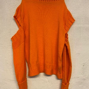 Stickad tröja - Stickad tröja ifrån Gina Tricot. Stark orange färg i verkligheten och har öppna detaljer på armarna. Är i mycket fint skick och kommer i storlek M. Köparen står för frakten