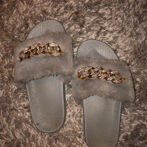 Grå tofflor med päls och smycke - Grå jötte fina tofflor, tyvärr för små för mig. Skulle passa st 35/36 tror jag. Använda.