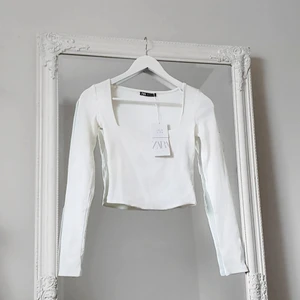 Zara Square tröja HELT NY !!! Strl S - Färg: vit.  Strl: S.  Material: 95% ekologisk bomull.  Långärmad tröja från Zara, detalj av fyrkantig urringning framtill, modern. Finribbat tyg i skön & fin kvalité. OBS. Aldrig använd, nyskick!! Lappar kvar!
