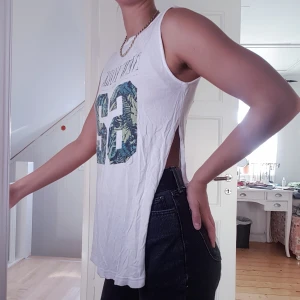 Långt linne med slit - Ett vitt långt linne med hög slit på båda sidor som går att styla på många olika sätt. Storlek M med sitter på mig som är S som den gör på bilden.