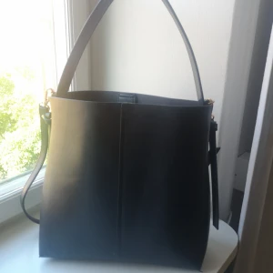  - Svart väska i läderimitation, tillhörande innerväska som också fungerar att använda separat 