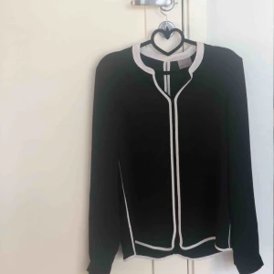  - En fin svart och vit blus ifrån VERO MODA som har en vit rand på sidan och knapp på ärmen i ryggen har den en öppning,använd fåtal gånger (frakt tillkommer)🙂
