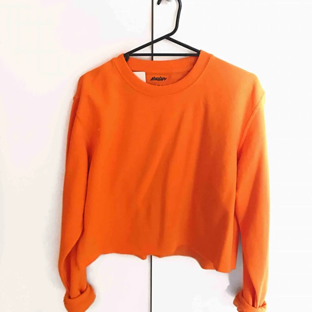 Orange croppad sweatshirt i färgen electric orange från MadLady. Aldrig använd, lappar sitter kvar på plagget. Storlek S/M. Köparen står för frakten - 50kr. Hoodies.