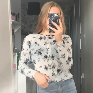 Blus - En liten genomskinlig gråblå blus med små svart blommor på. Den har knappar så man kan välja hur man vill att den sitter på. 30kr + frakt 22kr (tar bara swish)