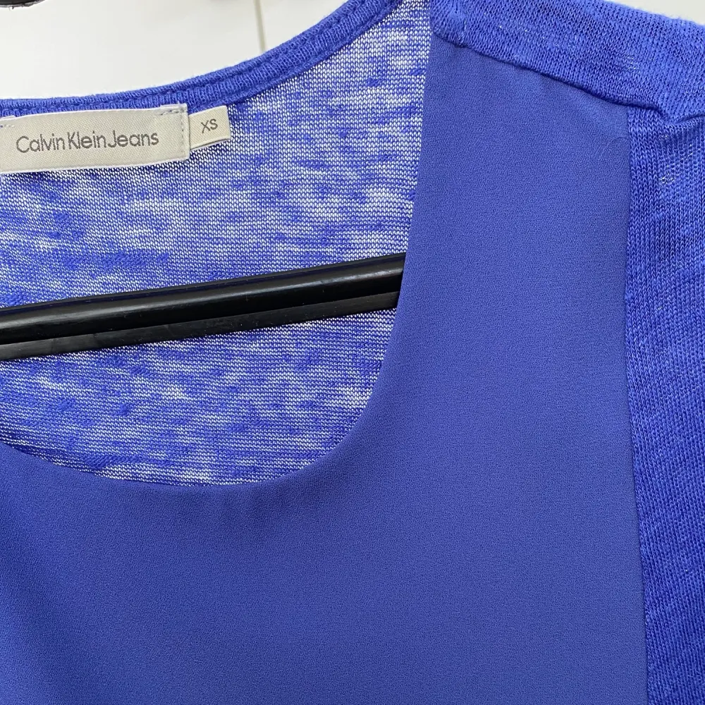 Säljer denna blå tröja utan ärmar från Calvin Klein Jeans. Väldigt fin och skön att bära under sommaren då materialet vid ärmarna och sidorna består av 100% linne medan tyget på framsidans mitt är gjord av en blandning av chiffon och polyester. . Toppar.