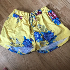 Mjukis shorts strl s - Säljer dessa mjukis shortsen som är gula med blå, rosa och vita blommor på. Jätte sköna och stora! Har även fickor på sidan av shortsen 