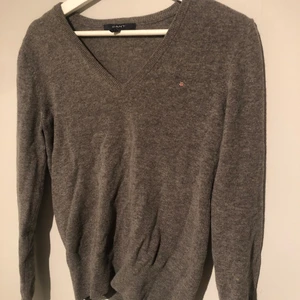 Gant tröja - Fin v-ringad tröja från gant i färgen grått och i storleken M. Har en jättefin passform och är i fint skick. Kontakta för mer information.
