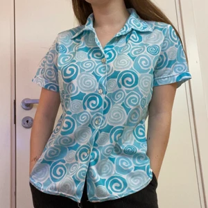 Skjorta - En skjorta i stretchigt material. Blå detaljer, luftig och i fint skick. Säljer pga kom inte till användning. Strl S/M. Köparen står för frakt.