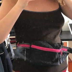 Rosa svart Midjeväska! - Aldrig använd. Köpt second hand. Knäppet är lite trasigt men det går att knäppa ändå. As ball bara. Ändringsbart band. 