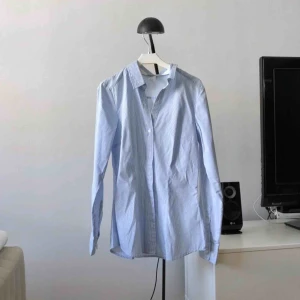  - Snygg ljusblå-randig skjorta från H&M. Knappt använd. (Frakt tillkommer om den ska skickas)