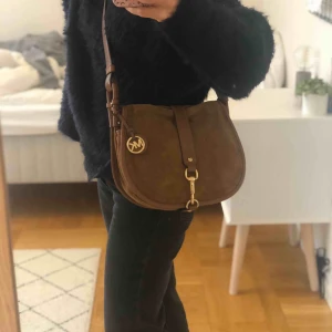 Michael Kors väska - Fin mockaväska från Michael Kors, använd ett fåtal gånger. Möts upp i Stockholm, annars står köparen för frakten. 