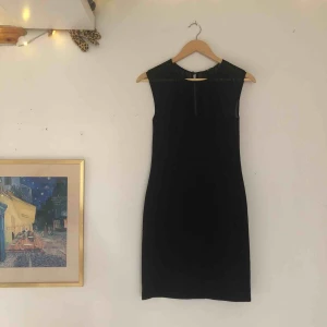  - Superfin svart klänning med mesh högst upp runt kanten. Den följer kroppens former och går lätt att ta på och av då det finns både dragkedja och knapp på baksidan. Klänningen har även en liten slits på baksidan.