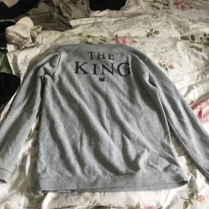 En långärmad grå tröja. Säljer åt en vän - Super mysig och skön. Helt grå långärmad men står ”the king” på baksidan. Perfekt att köpa till killen eller bara gå och mysa i den själv! Nästan aldrig använd.