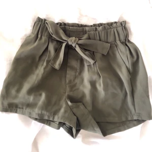 Shorts - Olivfärgade shorts med knyte där fram och resår i midjan. Mycket sköna och lagom långa! Perfekta sommarshorts ☀️