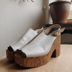Platåskor med korksula strl 39 - Drömskorna säljes! Okänt märke, men köpta secondhand. Någon liten reva i skinnet och sulan har vissa märken (se bilder) men annars i fint skick. Finns i Stadshagen/sthlm men skickas mot fraktkostnad.
