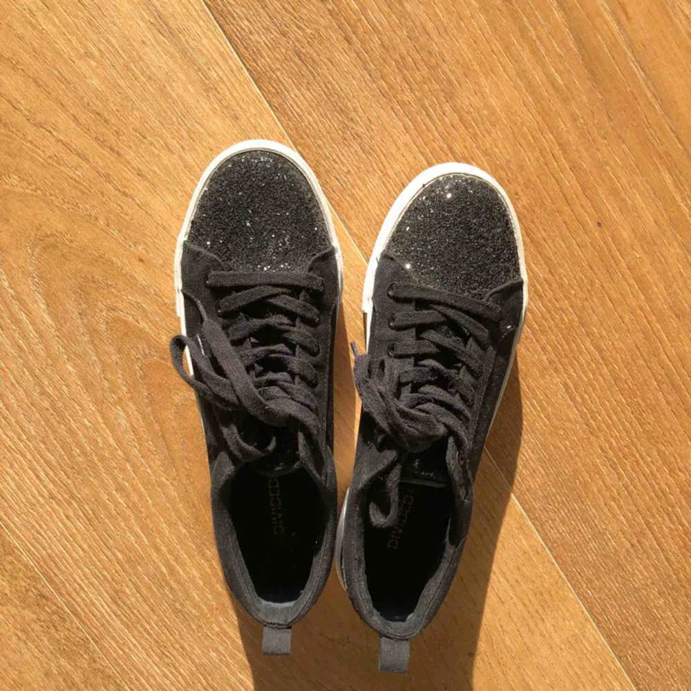 Höstens coolaste sneakers! Superfina platåsneakers i svart canvastyg. Svart glitter på främre och bakre delen av skon. Använda några få gånger men bra skick! Kan frakta mot fraktkostnad.. Skor.