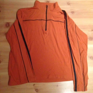  - Orange sportig vintage i använt skick, en liten fläck (se bild). Svarta sidenränder på sidan. 