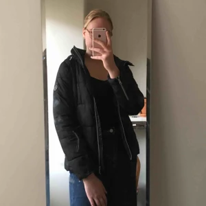  - Vinterjacka med luva. Svart med vinrött innertyg. Ungefär storlek 36-38. 