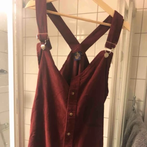  - Hängselklänning från beyond retro label. Väldigt bra skick, reglerbara hängselband. Kort, snygg med jeans under! Vinröd manchester