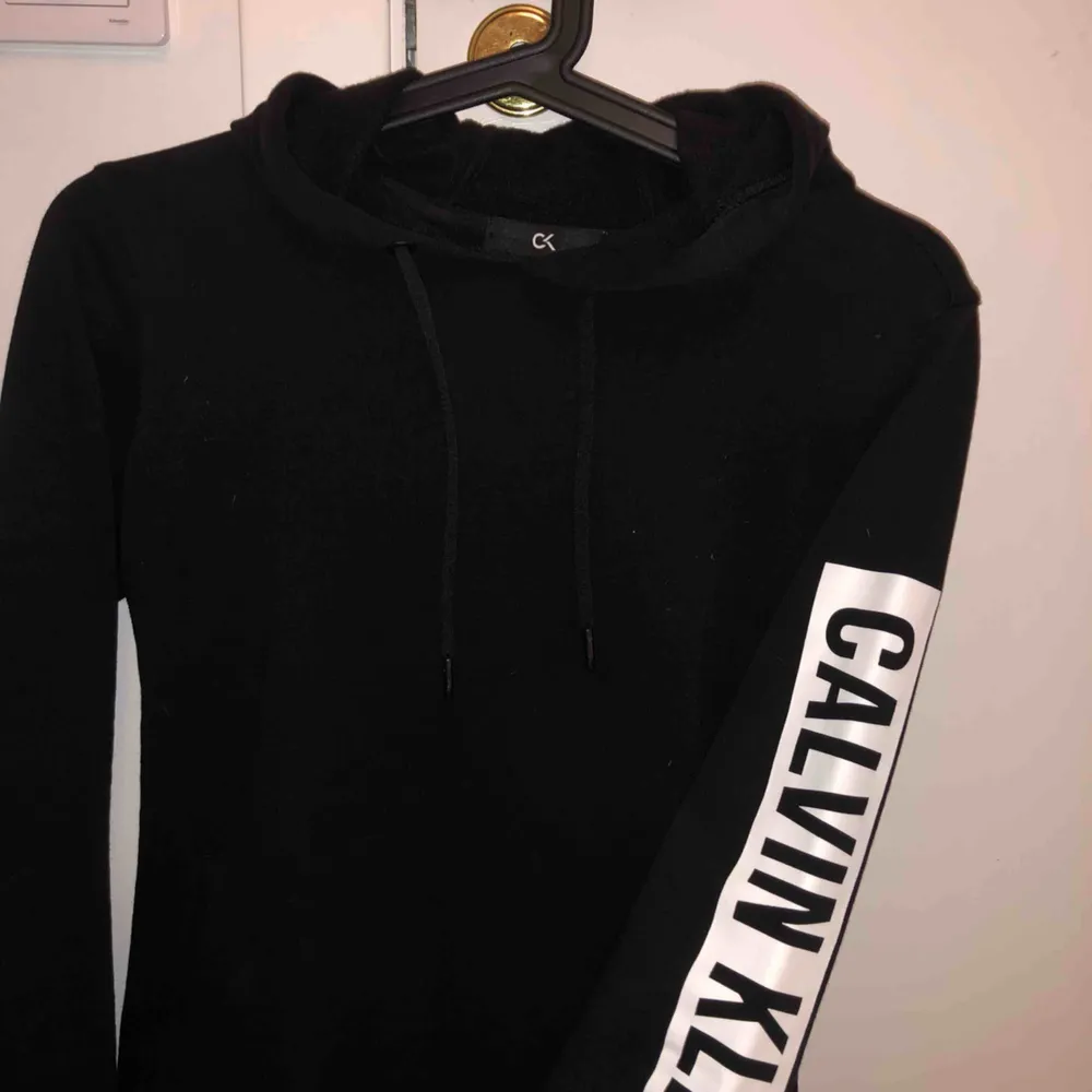 En svart hoodie från Calvin Klein med texten på ena armen Storlek XS Köpt från boozt är från Calvin Klein performance. Använd max 3 ggr. Hoodies.