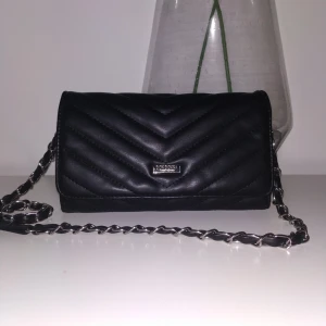  - Liten stilren väska från DON DONNA, finns hållare för kort. Får plats med mobil nycklar och kort i denna väska. Använd fåtal gånger. Inga repor eller skav på väskan. I nytt skick. Frakt på 79 kr, betalas av köparen