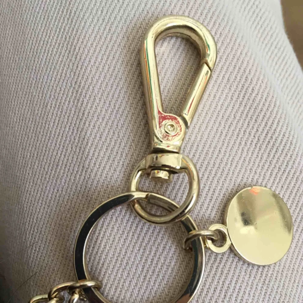En militärgrön fejk päls nyckelring, har aldrig använt denna. Med guld kedja, en dublon och ett knäppe. Accessoarer.