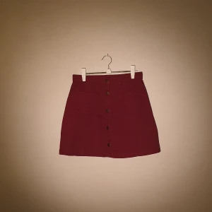 Kjol i storlek 36. - Röd jeanskjol med knappar från Monki i storlek 36. Priset är exklusive frakt.