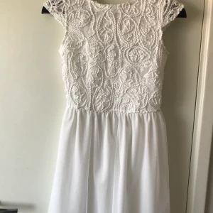 Vit studentklänning, bubbleroom, strl 34 - Vit klänning från bubbleroom i storlek 34. Tyll nedtill och brodering upptill. Stängs med knappar längs ryggen samt en kort dragkedja. Den är kritvit och perfekt till studenten! Använd en gång 🌸
