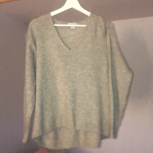 Beige sticka tröja  - En beige stickad tröja, vringad, lite längre där bak