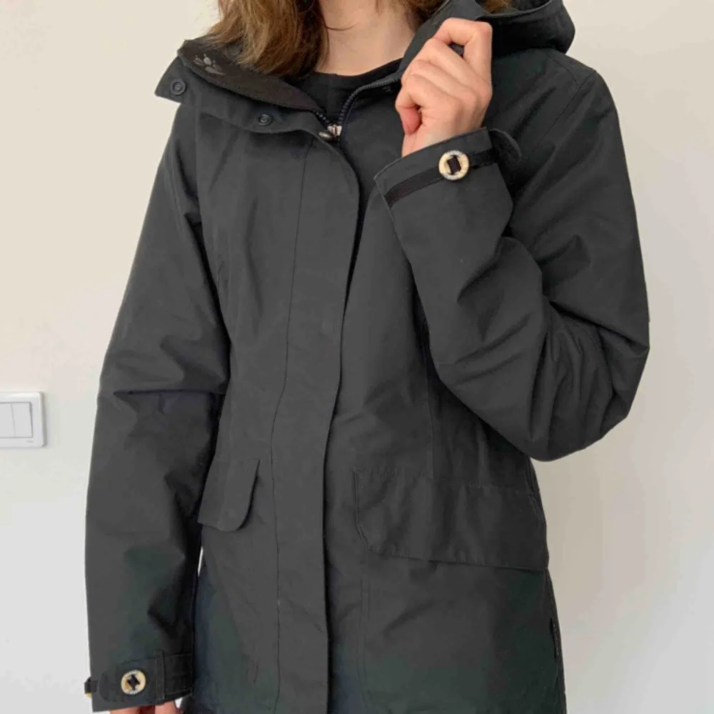 Jacket - waterproof & windproof Brand: Jack Wolfskin Size: S Colour: Charcoal Grey  Lots of nice little details, like wooden buttons.  Breathable. Weatherproof. You can make it tighter in the back.  Lots of pockets.  Hardly ever worn. Great condition. . Jackor.