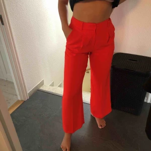  - Röda kostymbyxor med tillhörande midjeband. Köpta för 500 kr. Vida ben men tajt midja. Figurnära passform