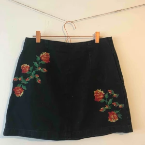  - Svart jeanskjol med röda broderade blommor på framsidan och dragkedja där bak från Topshop. Kjolen är i storlek 38 men skulle säga att den passar storlek 40 också. Knappt använd och i jättefint skick. 💞 Köparen står för frakt. 