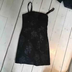Jättejättefin liten svart klänning från Urban Outfitters. Blommor på som också är i svart men lite glansigare material, smala axelband. Storlek XS och aldrig använt. Köpt för ca 700 kr förra året