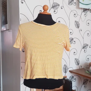 Randig monki-t-shirt säljes - Denna gul-vit-randiga t-shirt från Monki säljes då den inte längre används. Den har ett litet hål vid vänster axel som går att laga utan några problem. Passar både S och M! Skönt material!