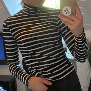 Svartvit långärmad polo - En randig polo som sitter skönt och bekvämt. Stretchigt material som lätt formar sig efter kroppen. 